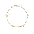 A delicate gold chain bracelet featuring five small celestial charms, including stars, moons, and a flower, laid out on a plain white background.