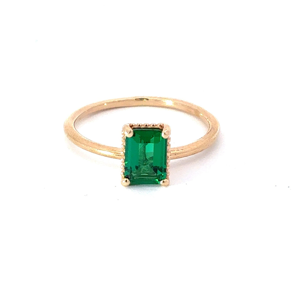Gold ring with a green gemstone on a white background